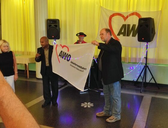 Ravindra Gujjula überreicht eine neue Fahne für die AWO Rüdersdorf an Sigrid Kieck.